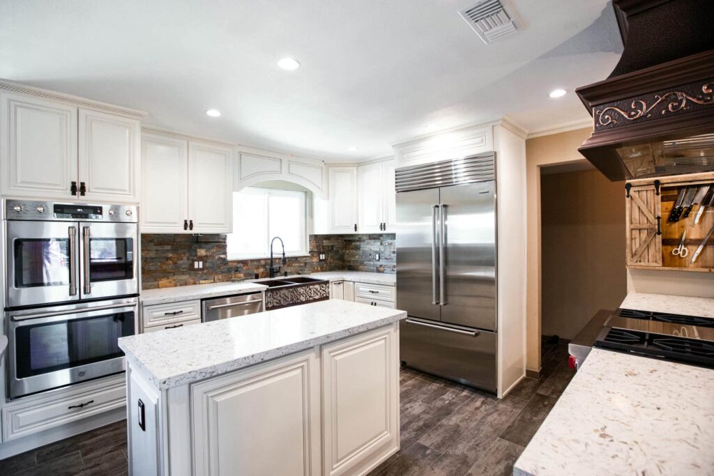 Remodeled Camino Calandria kitchen with detailed cabinetry, a wood range hood and a large white island