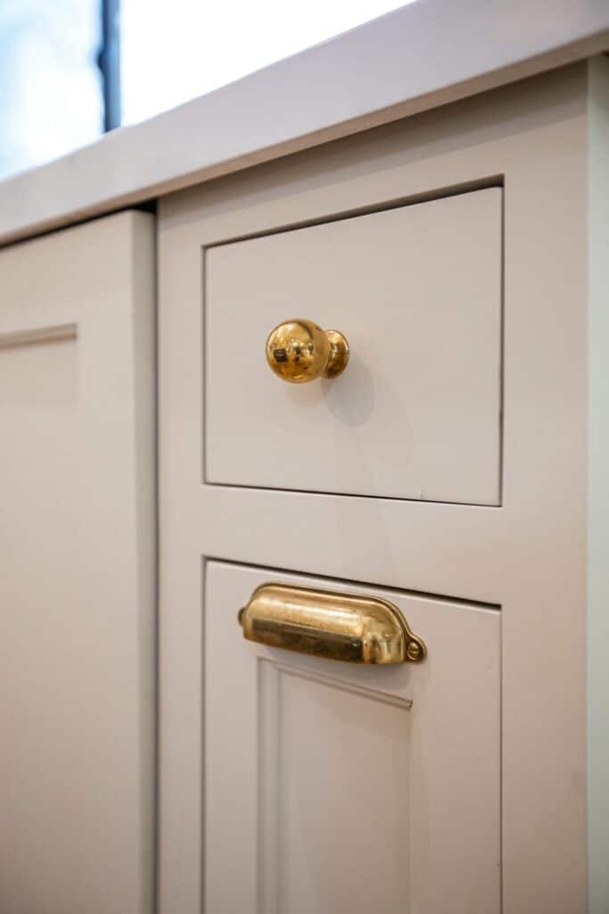 Brass knob and cup handle on white kitchen cabinetry at Zelzah Avenue