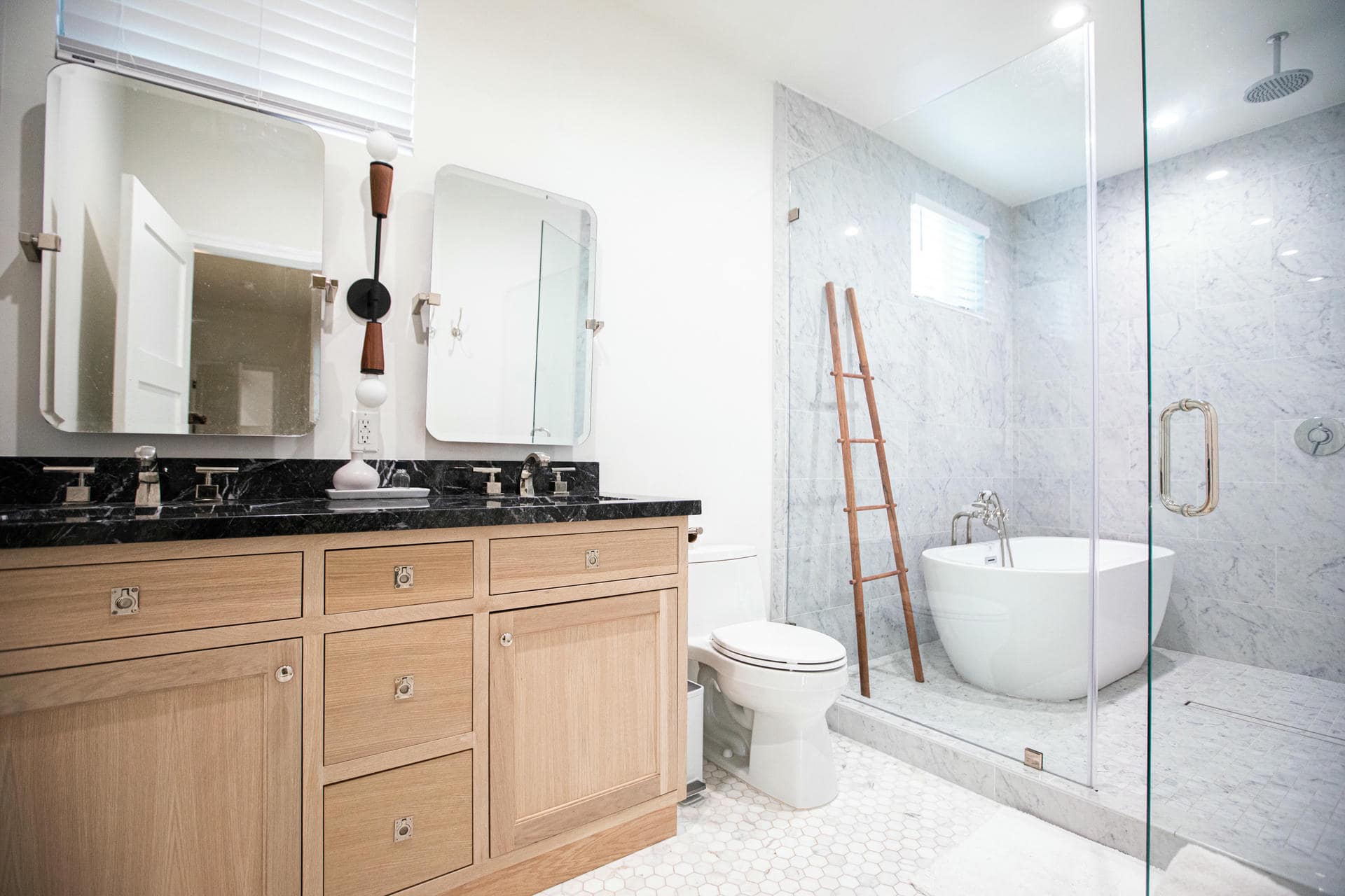 Wood vanity, dark countertop and glass shower in the completed Zelzah Avenue bathroom