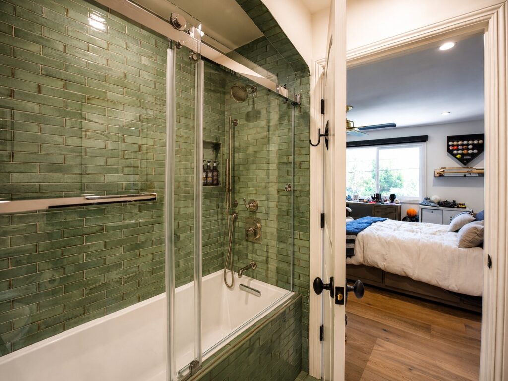 Green-tiled bathtub and shower with glass enclosure in the Loch Lomond home renovation